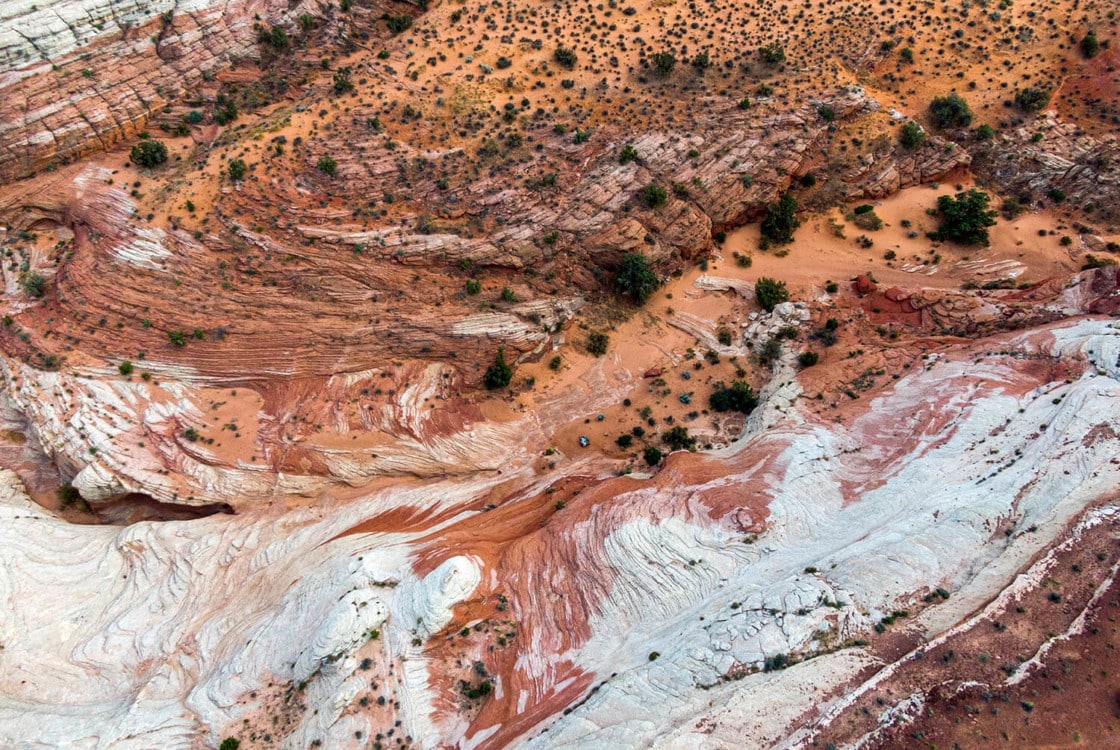 Colorful, layered rock formations interspersed with sparse vegetation in Southern Utah near Under Canvas Lake Powell.