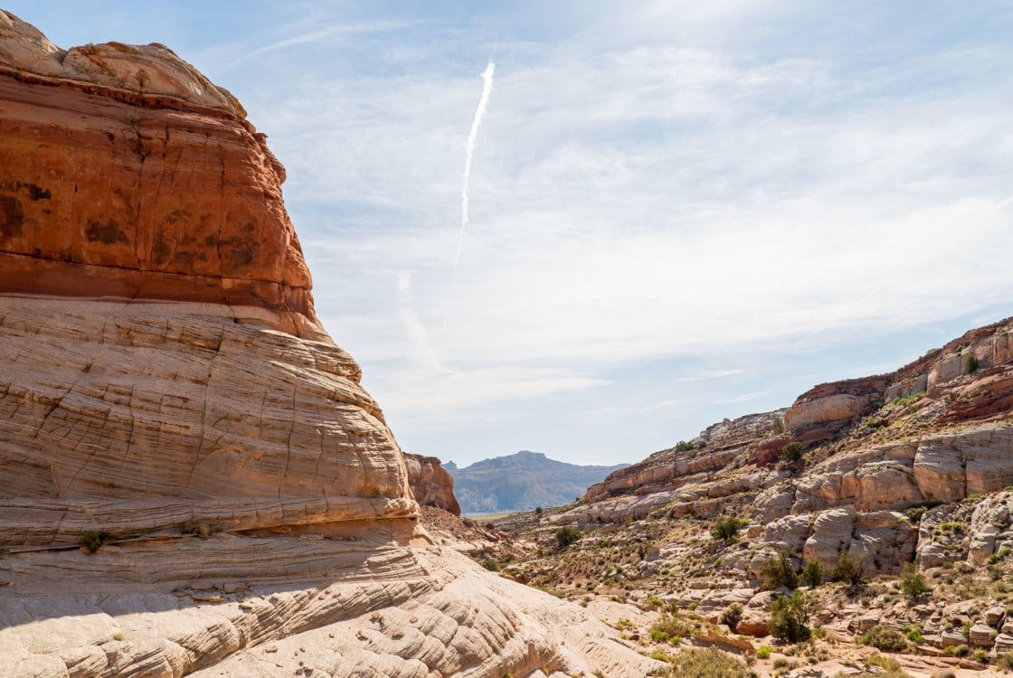 A massive, stratified rock formation stands prominently, surrounded by a sprawling desert landscape at Under Canvas Lake Powell.