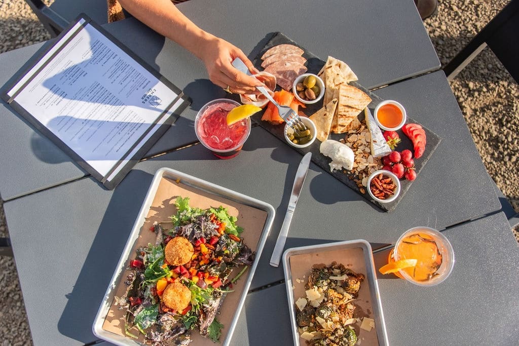 3 plates of food with a menu, and a hand reaching in to take a bite.