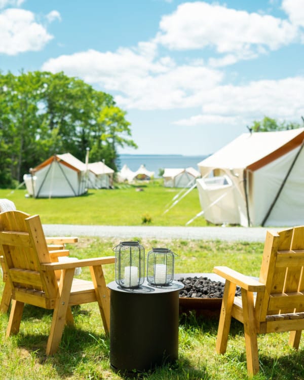 Chairs are set up around a fire pit overlooking the Under Canvas Acadia location.