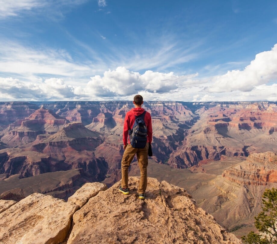 Person hiking standing above the Grand Canyon South Rim.
