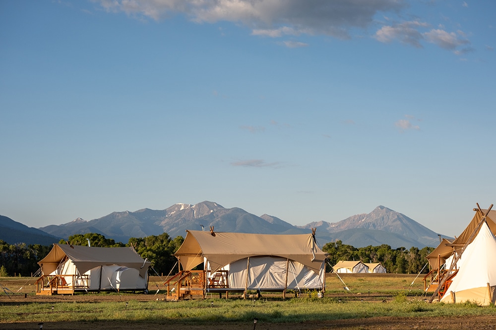 Tents with mountain range in the background at Under Canvas North Yellowstone - Paradise Valley