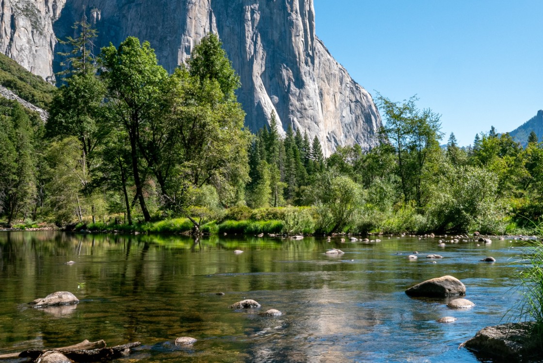 reflective water with towering rock ciff in background at Yosemite National Park