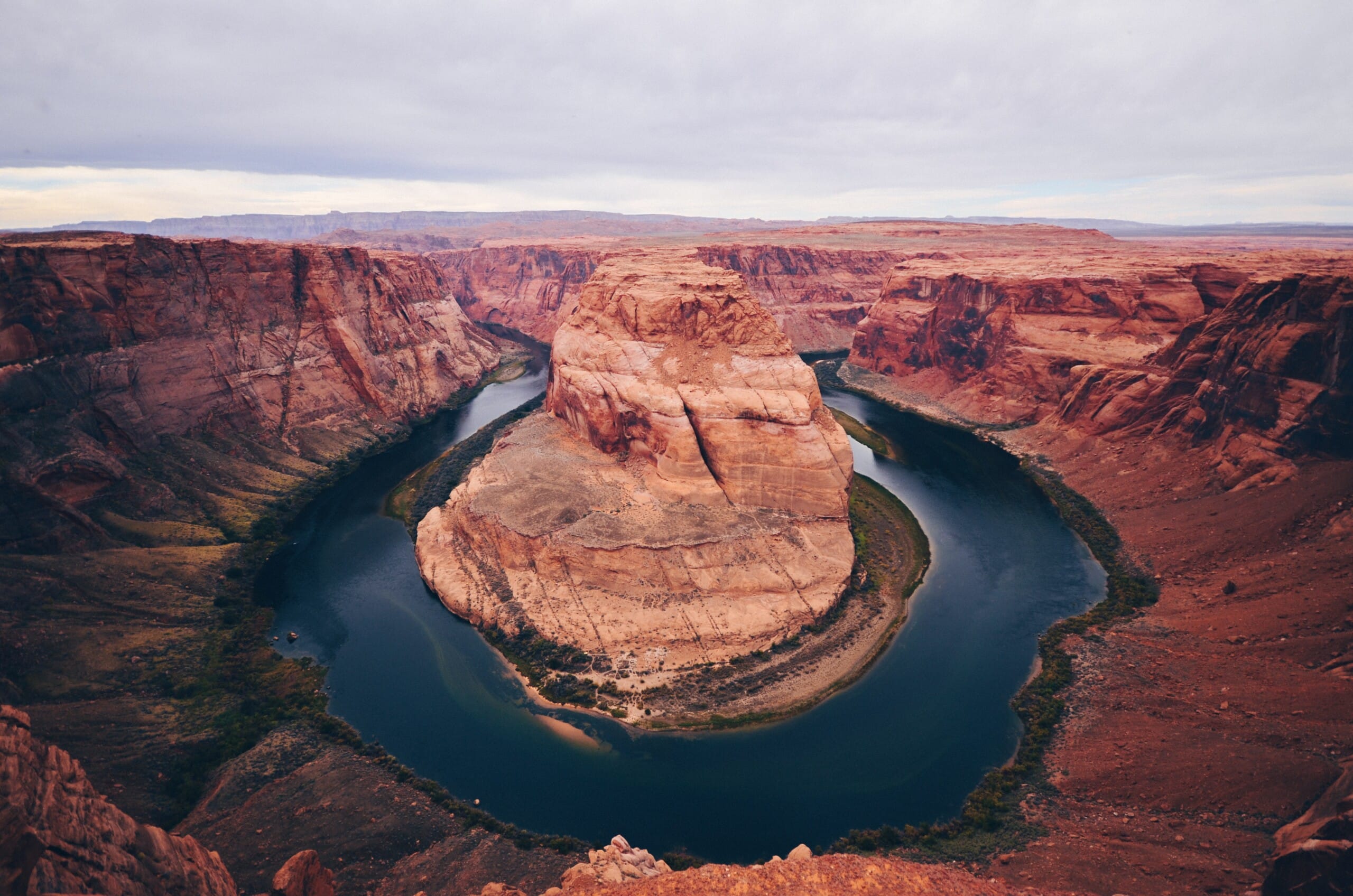 Person sitting on edge of the canyon at Horseshoe Bend