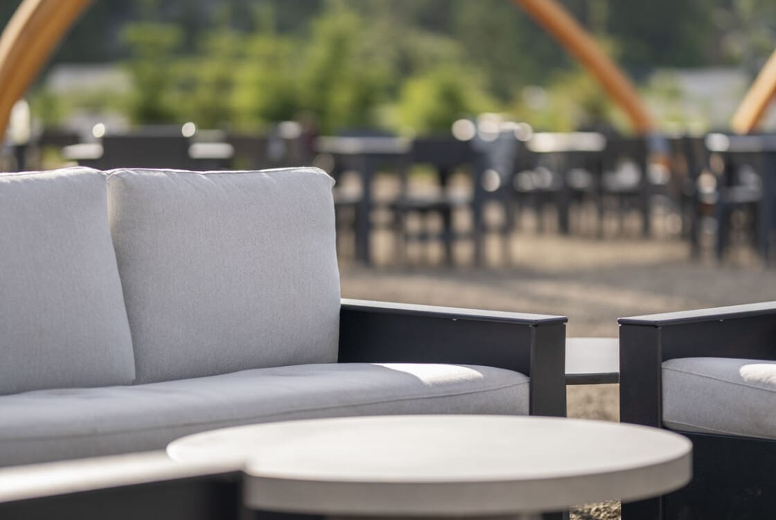 Outdoor lounge seating area with couch and round coffee table and tent structures in background