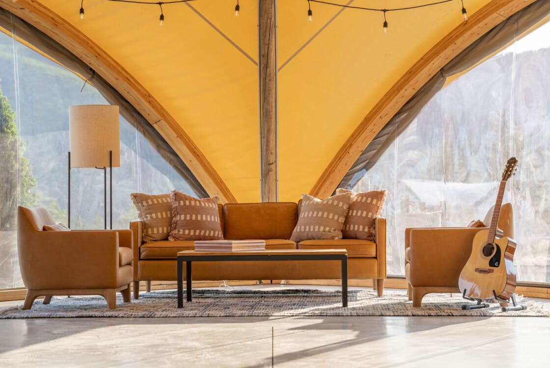 Lobby tent lounge area with couch, two lounge chairs and an acoustic guitar at Under Canvas Columbia River Gorge