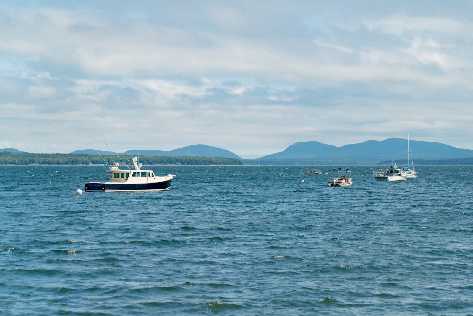 Fishing boats on a harbor in Maine with mountains in the background