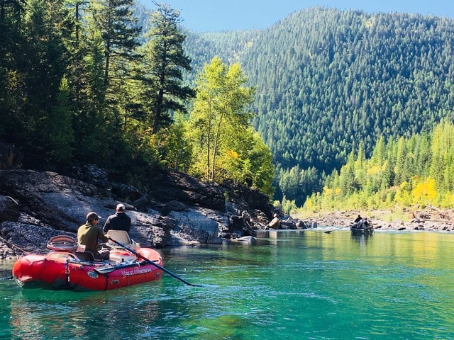Group of rafters on a clear blue river near Glacier National Park.