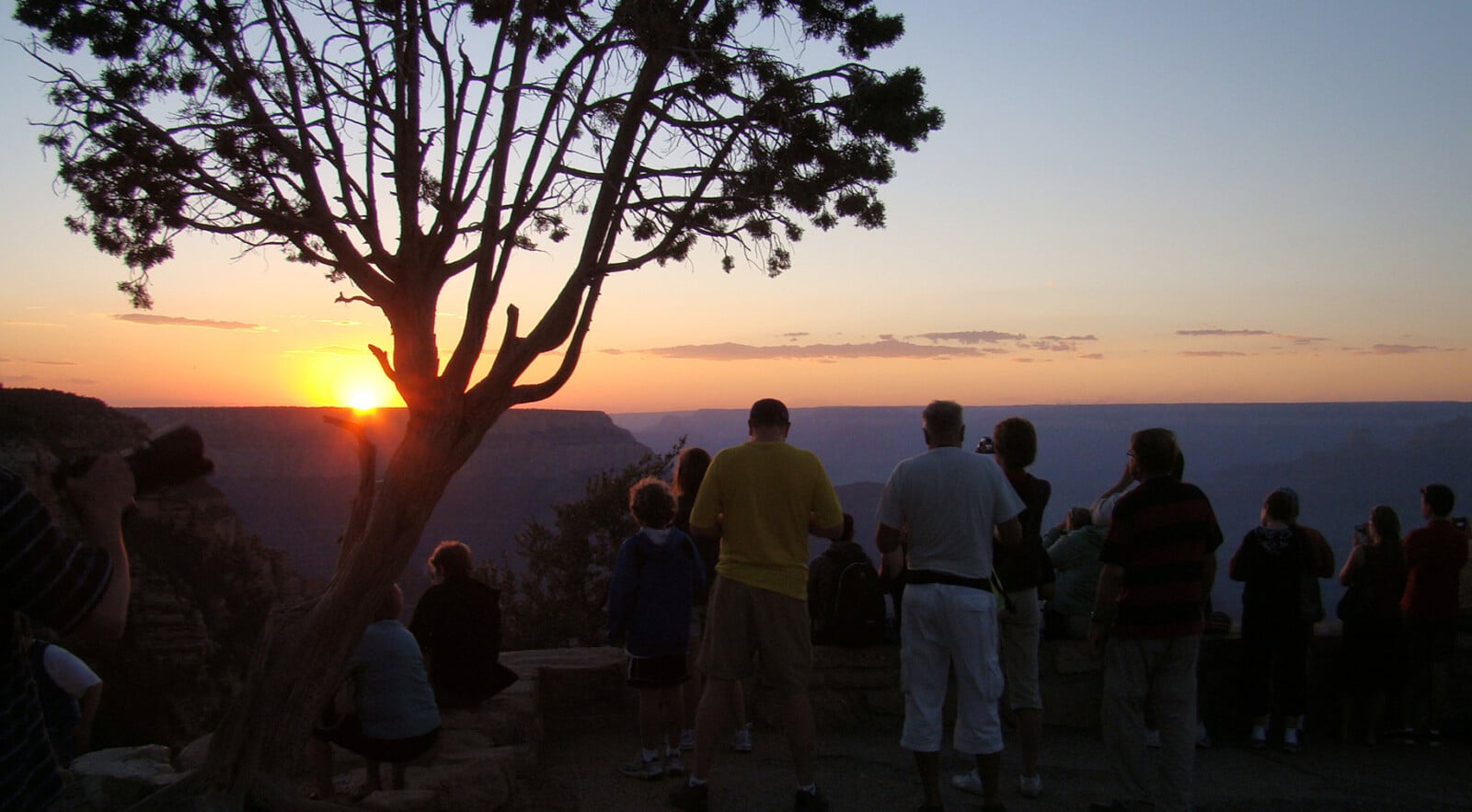 Group of people around the Grand Canyon Rim during sunset.