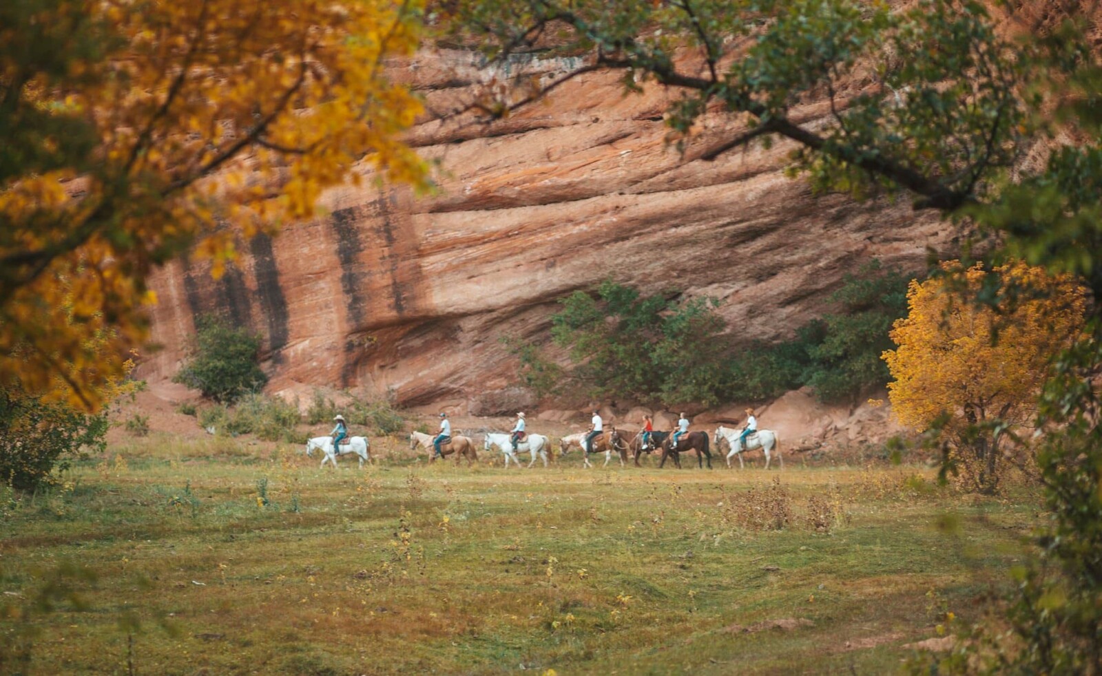 Group of horseback riders with a red rock backdrop