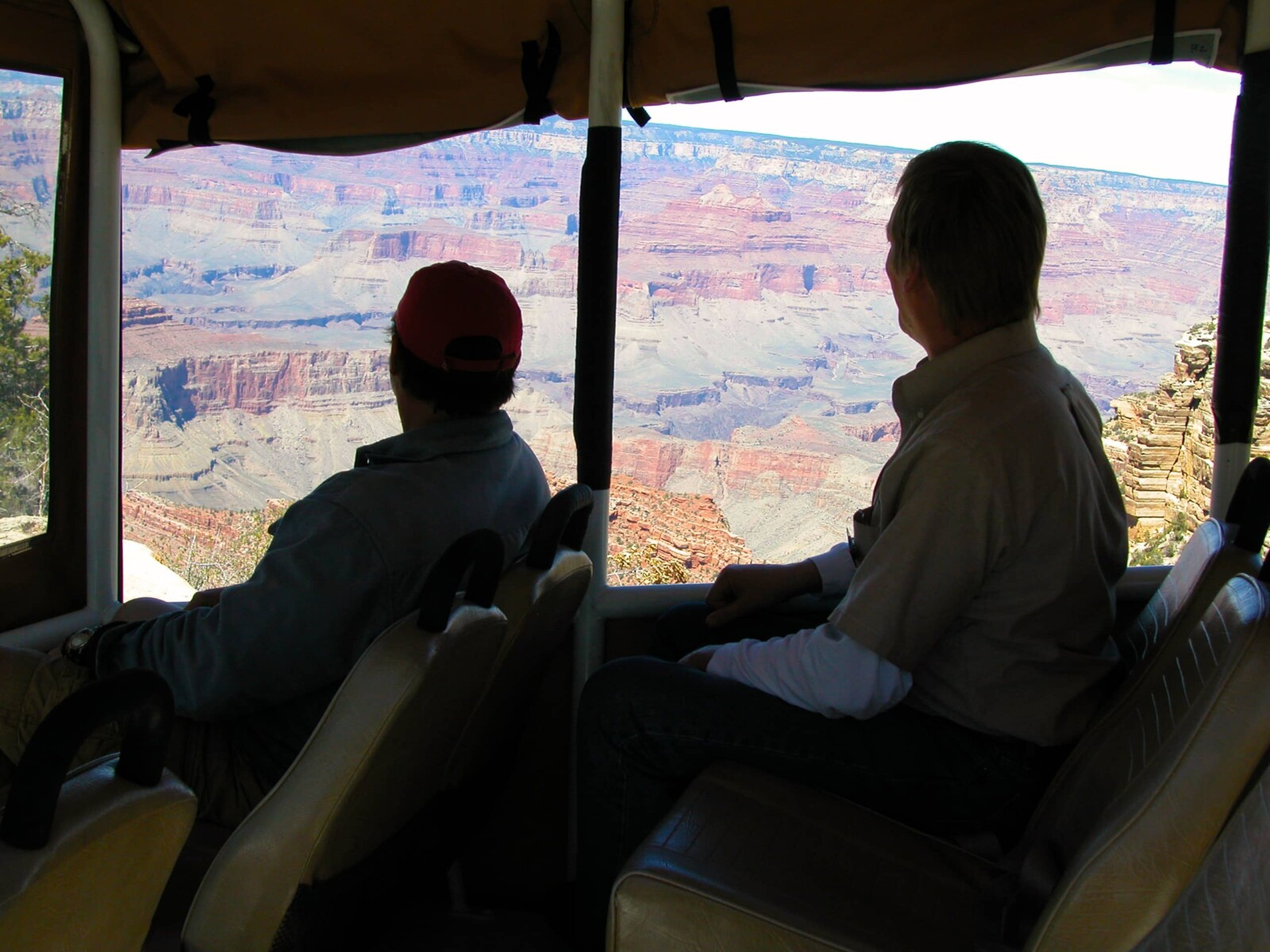 Guys in truck with a view of the Grand Canyon from the rim.