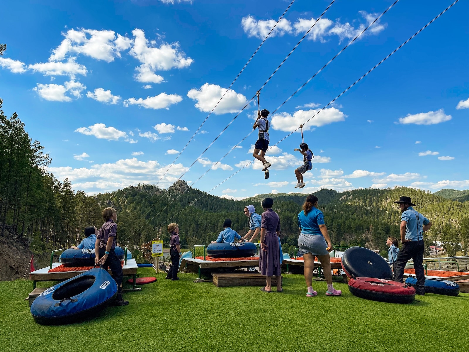 Adventure Park in the Black Hills of South Dakota with people on a zipline and others preparing for a mountain slide.