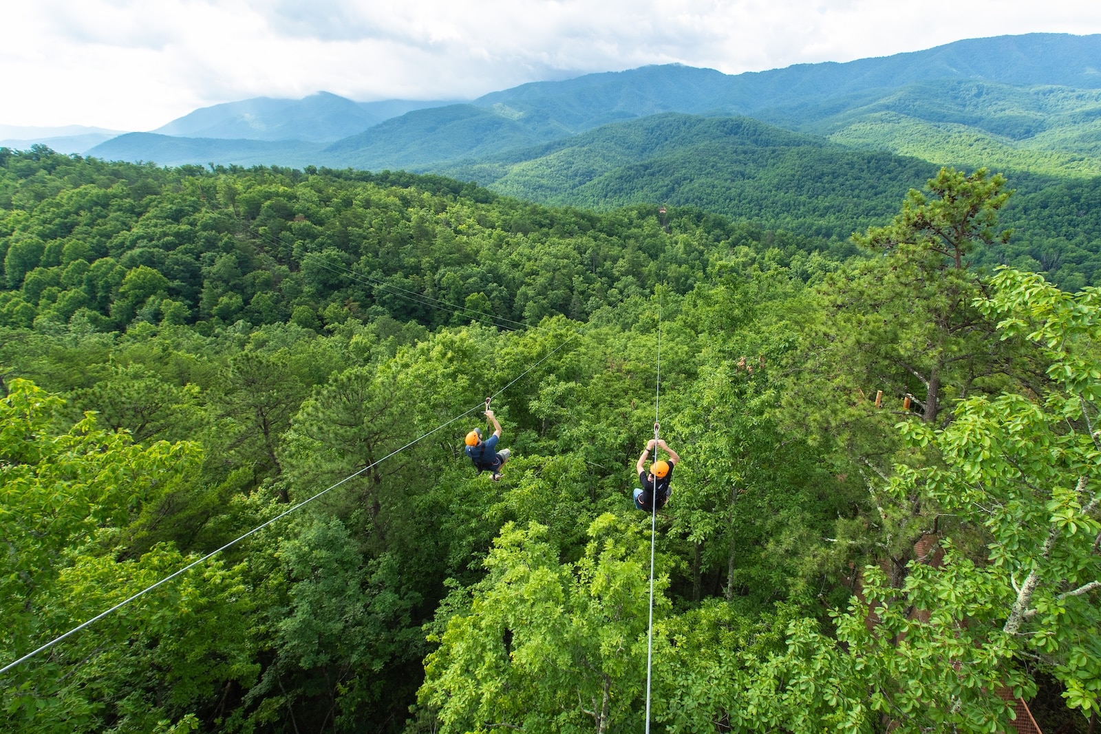 Two people ziplining over mountain tops near Smoky Mountains National Park.
