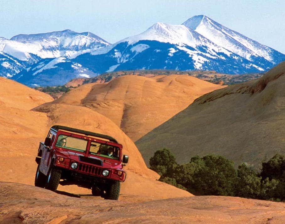 Group Hummer tour on red rocks with la sal mountains in the background.