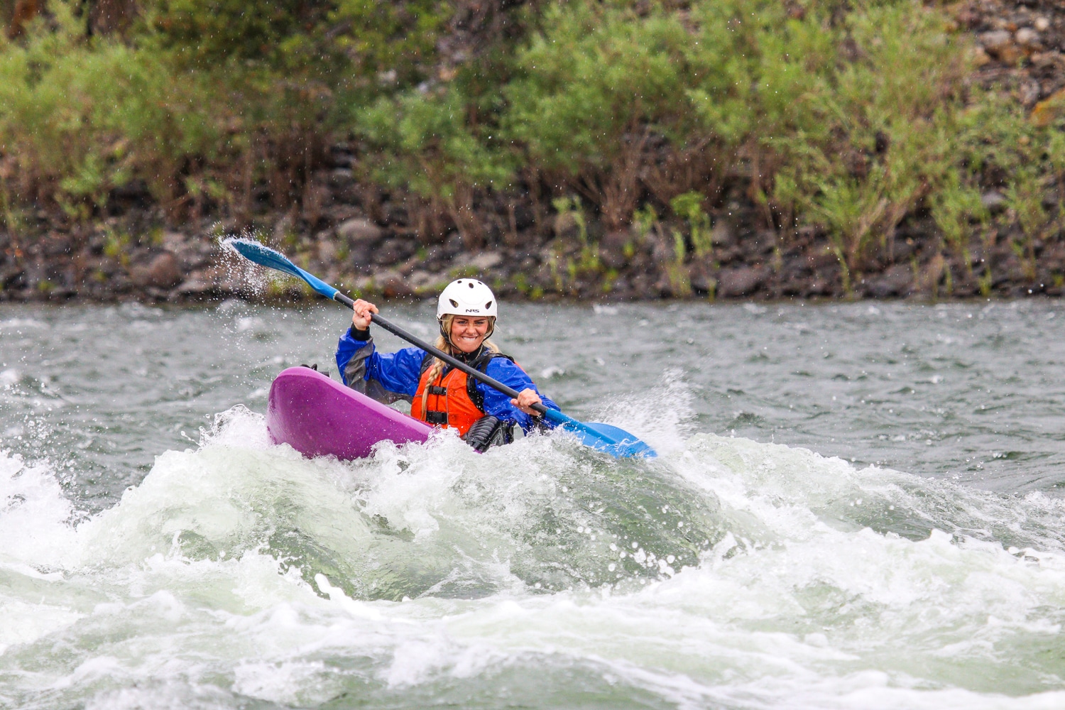 Woman white water kayaking going through a rapid.
