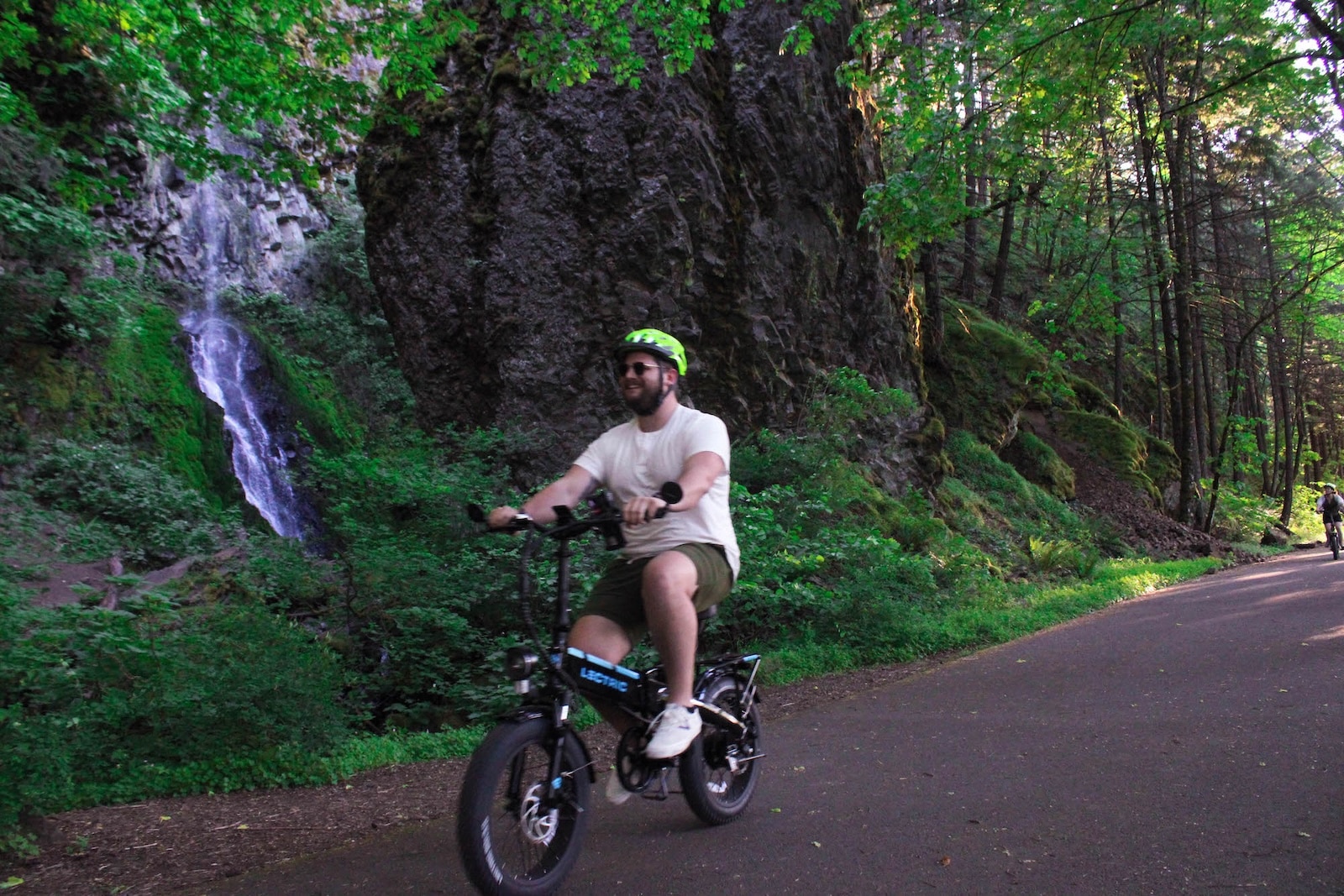 Man riding an ebike past a waterfall.