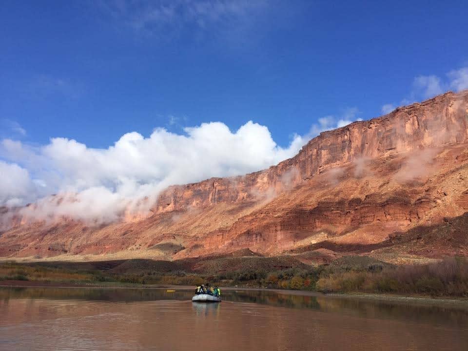 Rafting in Moab among large red rock cliffs.