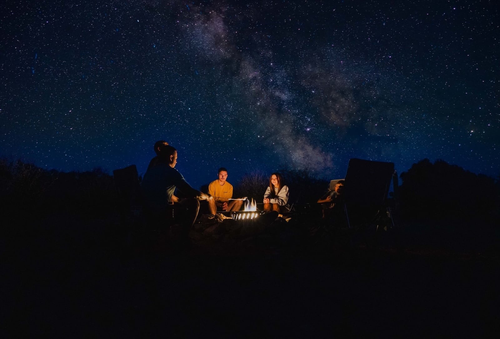 People around a fire stargazing near Bryce Canyon.