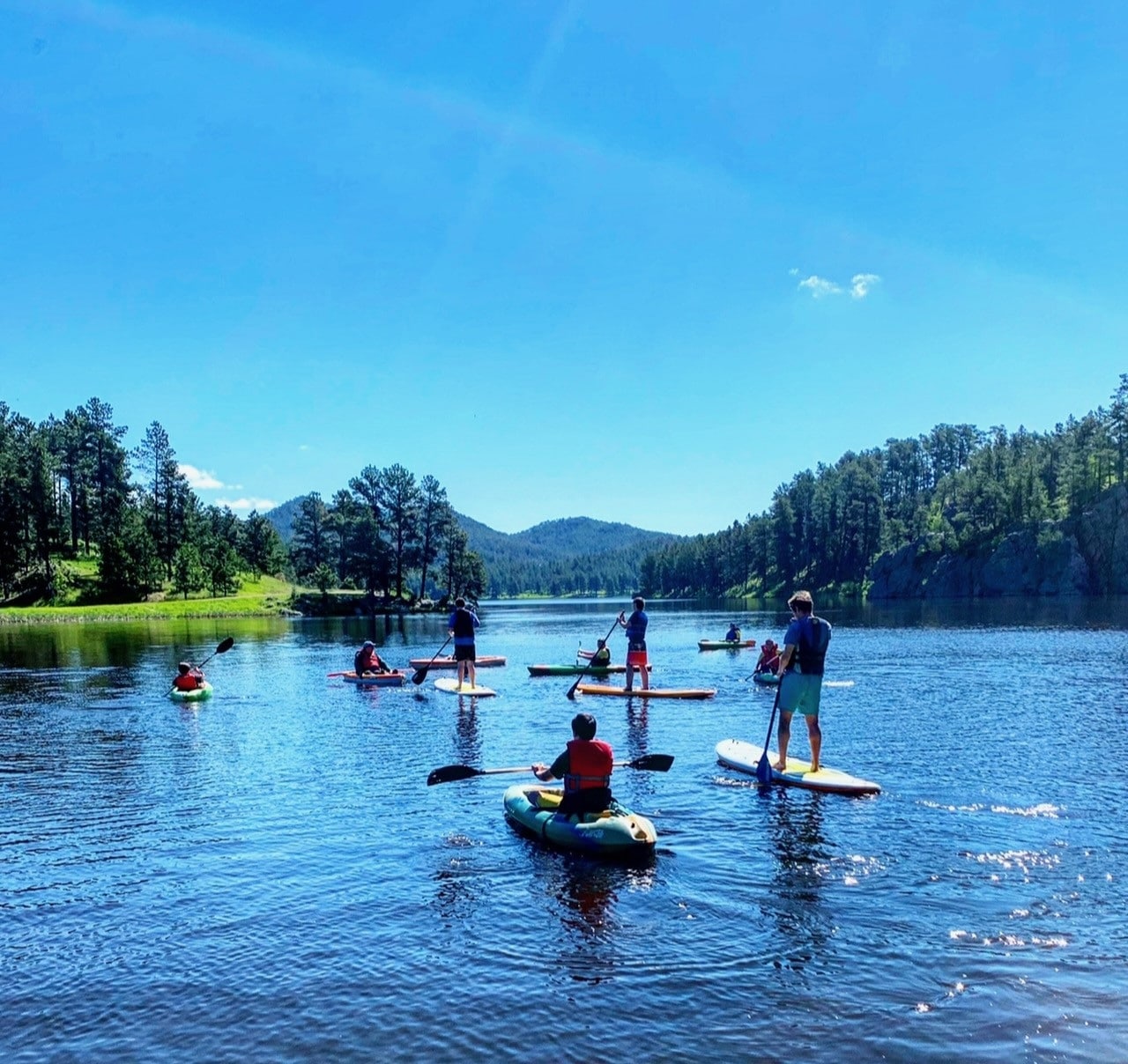 Group of paddle boarders and kayakers on Pactola Lake.