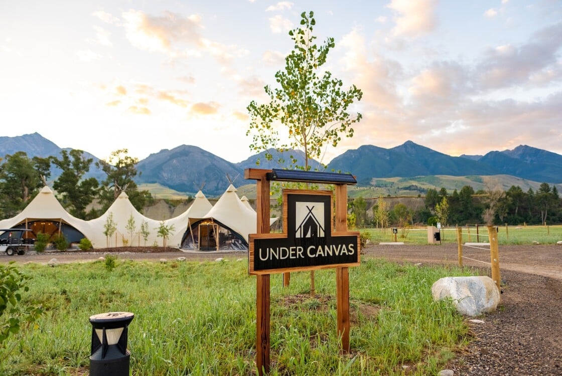 Under Canvas sign with a lobby tent and mountains in the background.