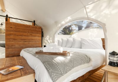 tent interior with chairs wood burning stove kind bed and star viewing window
